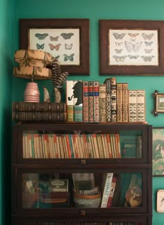 a bookshelf filled with lots of books next to framed pictures and other items