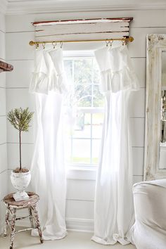 a window with white curtains and a potted plant