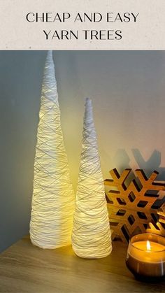 two white vases sitting on top of a wooden table next to a lit candle