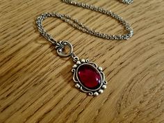 "This gorgeous Victorian era inspired necklace features a vibrant ruby red vintage Czech glass gem. The crystal is set in a burnished silver bezel. The bezel is made from brass using vintage tools and dies and then plated with sterling silver and oxidised to bring out the intricate details. The stainless steel chain is 18\" long finished with a lobster claw clasp." Coquette Necklace Silver Ruby, Vintage Ruby Necklace For Formal Occasions, Ornate Red Cabochon Jewelry, Red Oval Victorian Necklace, Red Vintage Necklace With Cabochon, Red Ruby Victorian Necklace, Vintage Red Cabochon Necklace, Red Vintage Cabochon Necklace, Vintage Ruby Pendant Jewelry