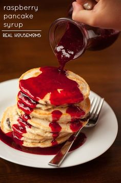 a stack of pancakes covered in raspberry pancake syrup on a white plate