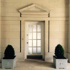 two potted plants sitting in front of a white door