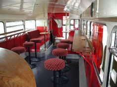 the inside of a bus with red seats and tables