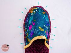 a crocheted slipper with colorful flowers and leaves on the bottom, sitting on top of a white surface