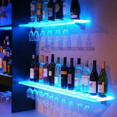 several bottles of wine are lined up on the shelves in a bar with blue lights