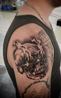 a man with a black and grey skull tattoo on his arm