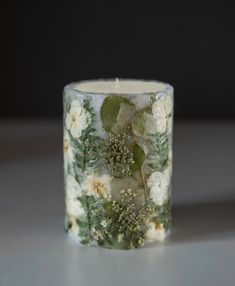 a candle that is sitting on a table with flowers and leaves painted all over it