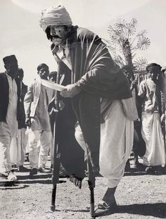 an old black and white photo of a man holding a cane in front of other men