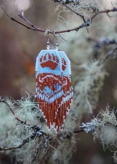 a beaded ornament hanging from a tree branch in front of some branches