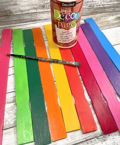 a can of paint sitting on top of rainbow colored strips of wood