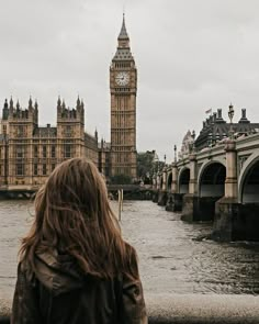 a woman standing in front of the big ben clock tower