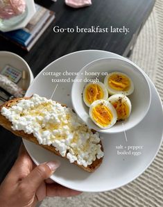 a person holding a plate with eggs and cottage cheese on it