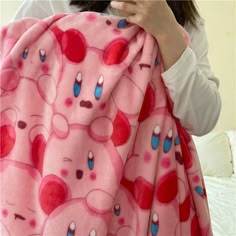 a woman holding up a pink teddy bear blanket