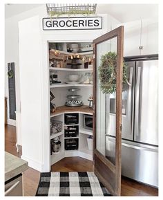 an open pantry door in the corner of a kitchen with white walls and wood floors