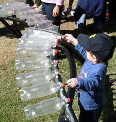 a young boy is playing with water bottles on a conveyor belt while others watch