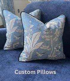 two blue pillows sitting on top of a blue couch in front of a window with the words custom pillows written below them