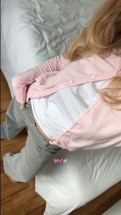 a woman laying on top of a bed next to a white comforter and pillows