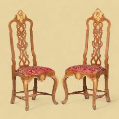 two wooden chairs with red upholstered seats and gold trimmings on them