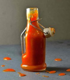 an orange sauce in a glass bottle with a sprinkler sticking out of it