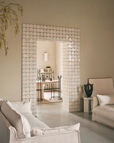 a living room filled with white furniture and walls covered in decorative wallpaper, as well as a mirror