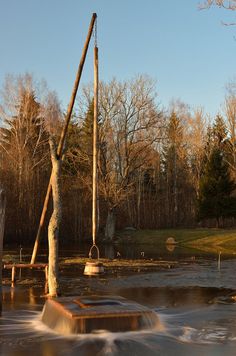 the water is rushing over the wooden structure in the middle of the park with trees around it