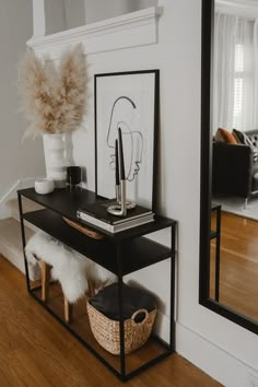 a black and white shelf with some pictures on it next to a mirror in a living room