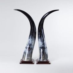 two black and white vases sitting on top of a wooden stand with long curved ends