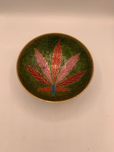 a green and red bowl sitting on top of a white table next to a wall