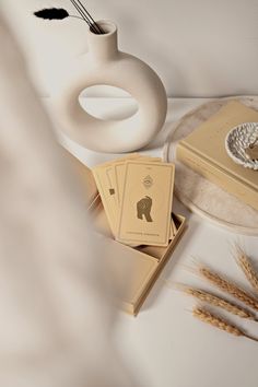 a white vase sitting on top of a table next to some cards and a box