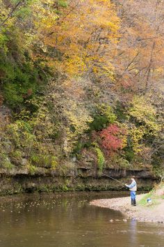 a man fishing on the river in autumn