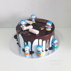 there is a chocolate cake with frosting and small figures on the top, sitting on a silver platter