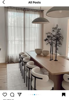 a dining room table with chairs and vases on top of it, in front of a large window