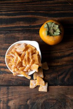 an orange sitting next to a bowl filled with food on top of a wooden table