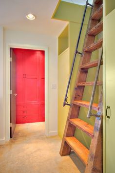 a red door is next to a wooden ladder