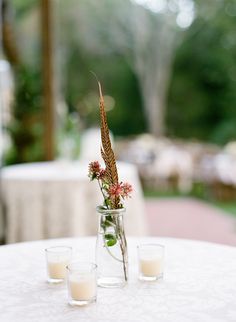 two vases filled with flowers and candles on top of a white cloth covered table