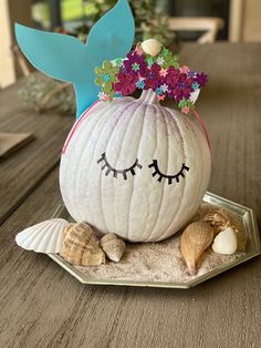 a white pumpkin decorated with flowers and seashells