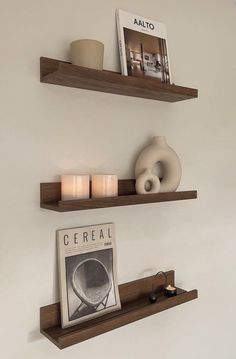 two wooden shelves with candles and pictures on them in a living room setting, one shelf is holding magazines