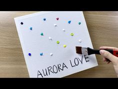 someone is painting the words aurora love on a piece of paper