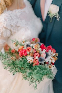 the bride and groom are holding their wedding bouquets in their hands while they stand close to each other