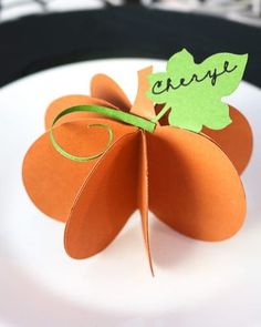 an orange paper flower sitting on top of a white plate