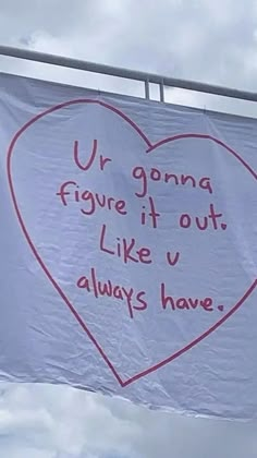 a large white banner with writing on it in the shape of a heart hanging from a metal bar