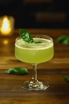 a glass filled with a green drink sitting on top of a wooden table