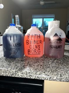 three plastic jugs with writing on them sitting on top of a counter in a kitchen