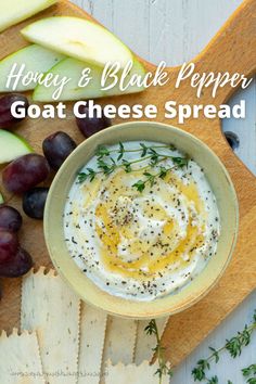 a bowl of goat cheese spread next to sliced apples and grapes on a cutting board