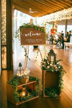 a wooden sign sitting on top of a floor next to two boxes filled with flowers