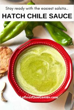 a red bowl filled with green sauce next to some vegetables