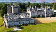 an aerial view of a castle with trees and water in the background