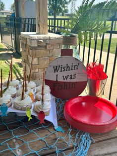 cupcakes and other treats are on a table outside near a sign that says wishin i was fishin