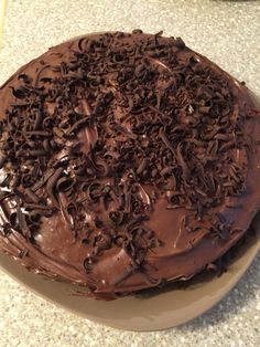 a chocolate cake on a plate with frosting and sprinkles