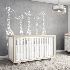 a baby's room with giraffe decals on the wall and crib